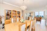 Experience elegant dining in this beautifully appointed space, featuring a large wooden table set for gatherings and a stunning crystal chandelier overhead.