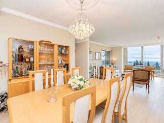 Experience elegant dining in this beautifully appointed space, featuring a large wooden table set for gatherings and a stunning crystal chandelier overhead.