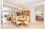 This elegant dining room features a large, light wood table with upholstered chairs, perfect for hosting gatherings.
