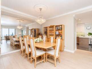 This elegant dining room features a large, light wood table with upholstered chairs, perfect for hosting gatherings.