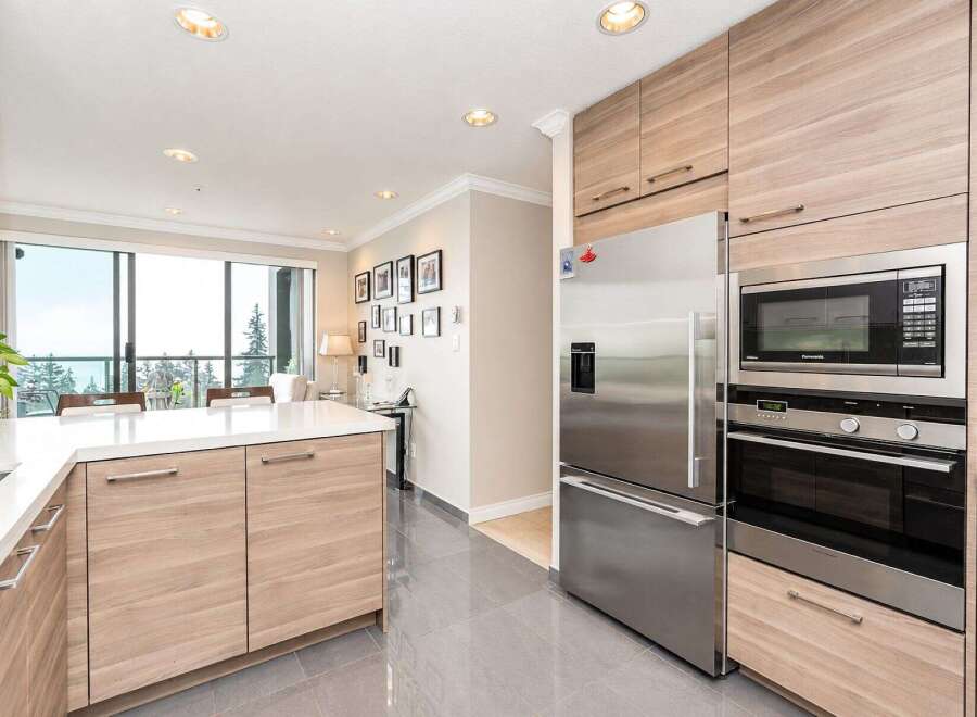 Experience modern living in this stunning kitchen featuring sleek, light wood cabinetry and a spacious white quartz island, perfect for meal preparation and casual dining.