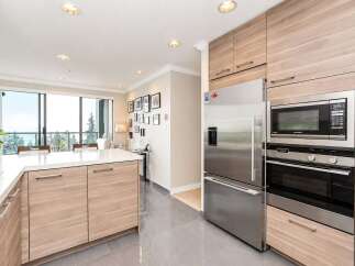 Experience modern living in this stunning kitchen featuring sleek, light wood cabinetry and a spacious white quartz island, perfect for meal preparation and casual dining.