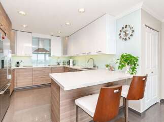 Experience modern living in this stunning kitchen featuring sleek white cabinetry and warm wood accents.