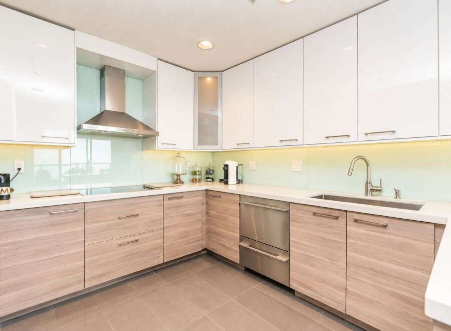 Experience modern luxury in this stunning kitchen, featuring sleek white cabinetry and warm wood lower cabinets.