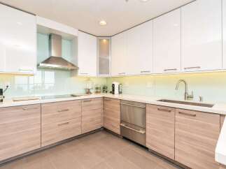 Experience modern luxury in this stunning kitchen, featuring sleek white cabinetry and warm wood lower cabinets.