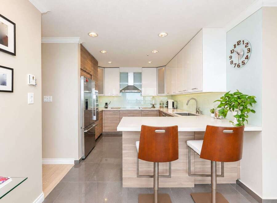 Experience modern living in this stunning kitchen featuring sleek white cabinetry, warm wood accents, and a spacious island perfect for entertaining.