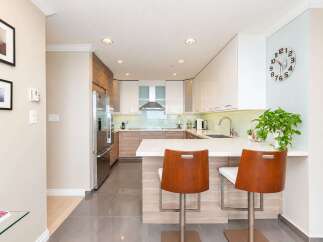 Experience modern living in this stunning kitchen featuring sleek white cabinetry, warm wood accents, and a spacious island perfect for entertaining.