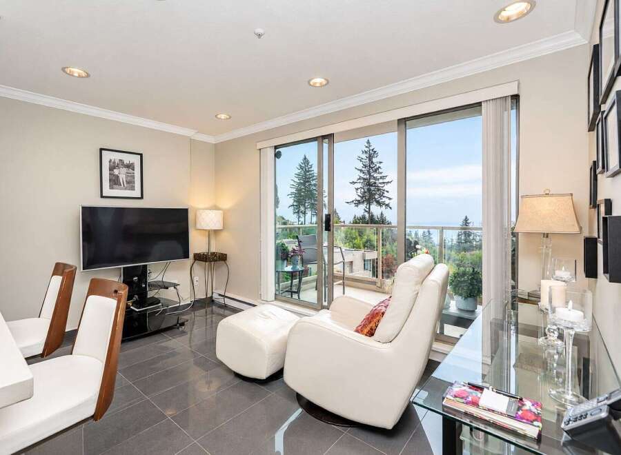 Enjoy breathtaking ocean and mountain views from this stunning living space, featuring a comfortable recliner and ottoman perfect for relaxation.