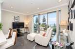Enjoy breathtaking ocean and mountain views from this stunning living space, featuring a comfortable recliner and ottoman perfect for relaxation.