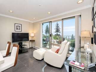 Enjoy breathtaking ocean and mountain views from this stunning living space, featuring a comfortable recliner and ottoman perfect for relaxation.