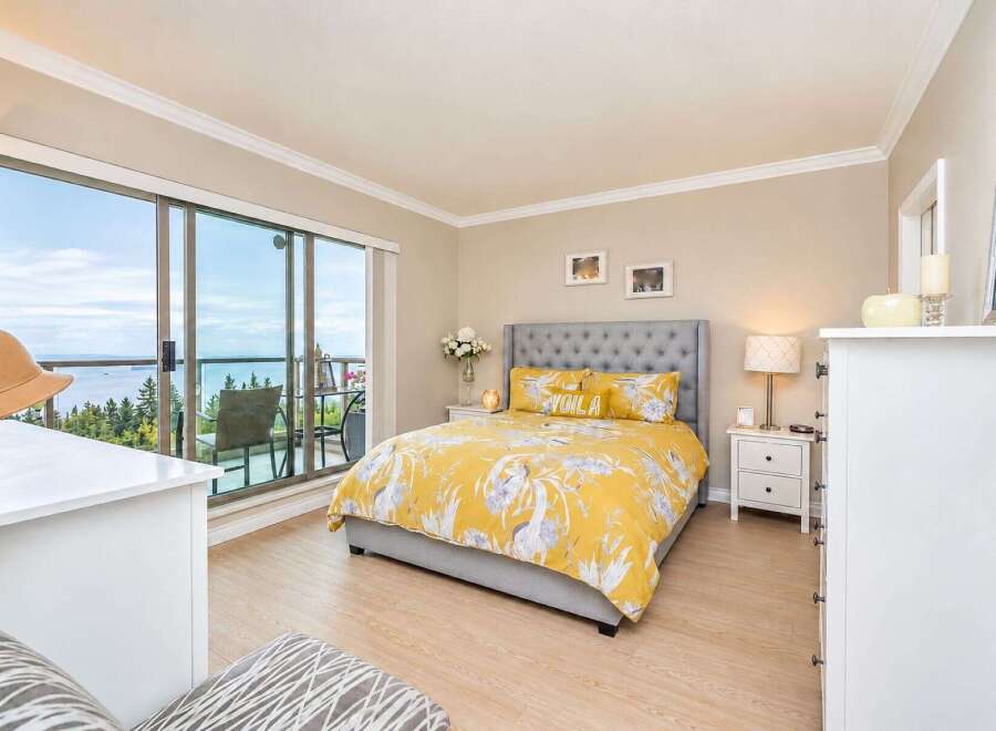 Experience breathtaking ocean views from this stunning bedroom, featuring a luxurious king-size bed with vibrant yellow floral bedding.