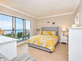 Experience breathtaking ocean views from this stunning bedroom, featuring a luxurious king-size bed with vibrant yellow floral bedding.