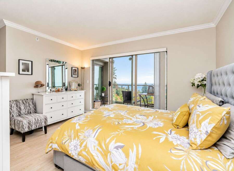 Experience breathtaking ocean views from this stunning bedroom, featuring a luxurious king-sized bed with a vibrant floral duvet.