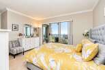 Experience breathtaking ocean views from this stunning bedroom, featuring a luxurious king-sized bed with a vibrant floral duvet.