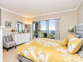 Experience breathtaking ocean views from this stunning bedroom, featuring a luxurious king-sized bed with a vibrant floral duvet.