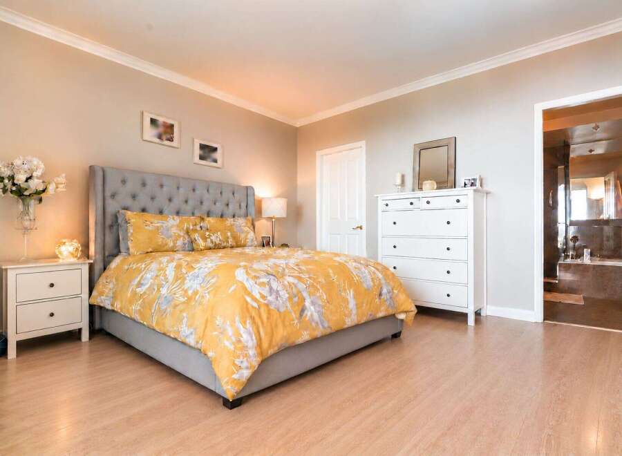 This inviting bedroom features a plush, tufted headboard and a vibrant yellow floral duvet, creating a cozy and stylish retreat.