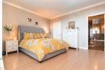 This inviting bedroom features a plush, tufted headboard and a vibrant yellow floral duvet, creating a cozy and stylish retreat.