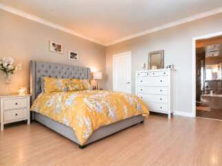 This inviting bedroom features a plush, tufted headboard and a vibrant yellow floral duvet, creating a cozy and stylish retreat.