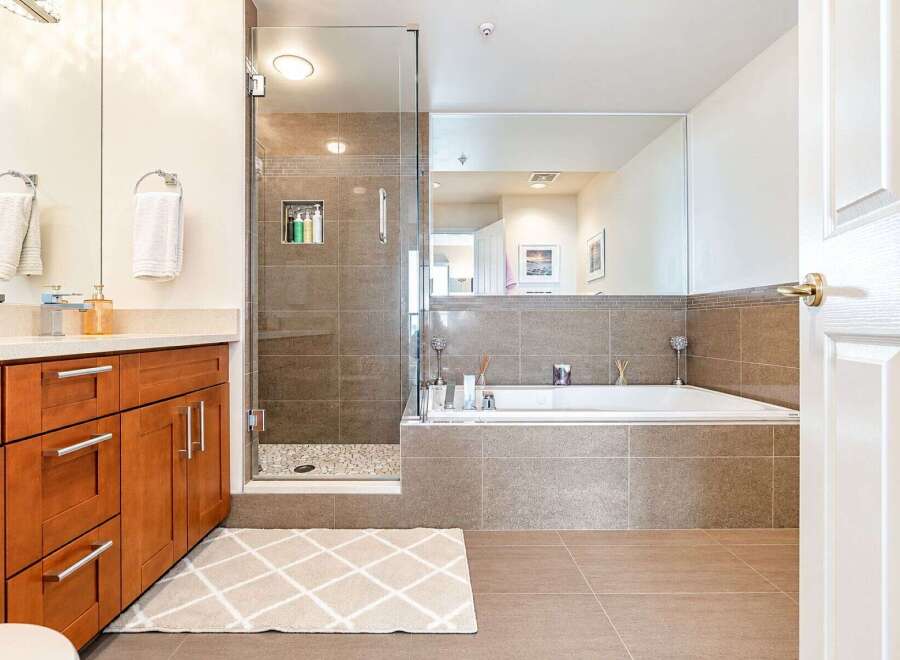 Experience luxury in this modern bathroom featuring a spacious glass-enclosed shower with tiled walls and a pebble floor.