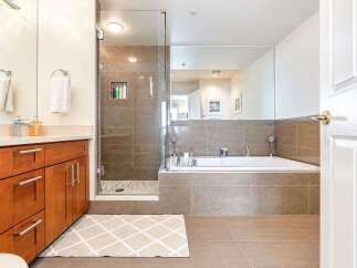 Experience luxury in this modern bathroom featuring a spacious glass-enclosed shower with tiled walls and a pebble floor.