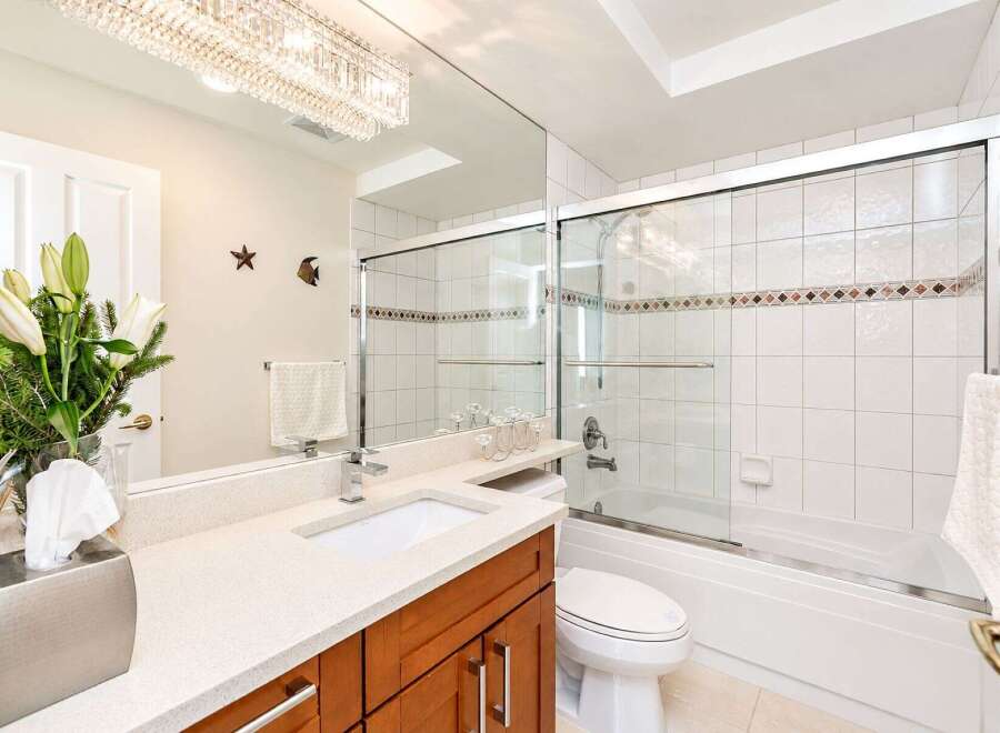This elegant bathroom features a spacious vanity with a quartz countertop and a modern undermount sink, complemented by a warm wood cabinet.