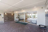Welcome to this inviting building entrance, featuring a modern glass facade and a well-maintained brick walkway.