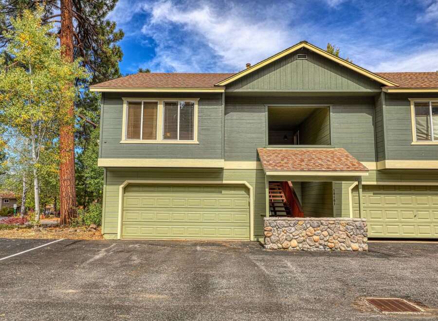 This charming property features a two-story design with a light green exterior and a complementary tan trim.