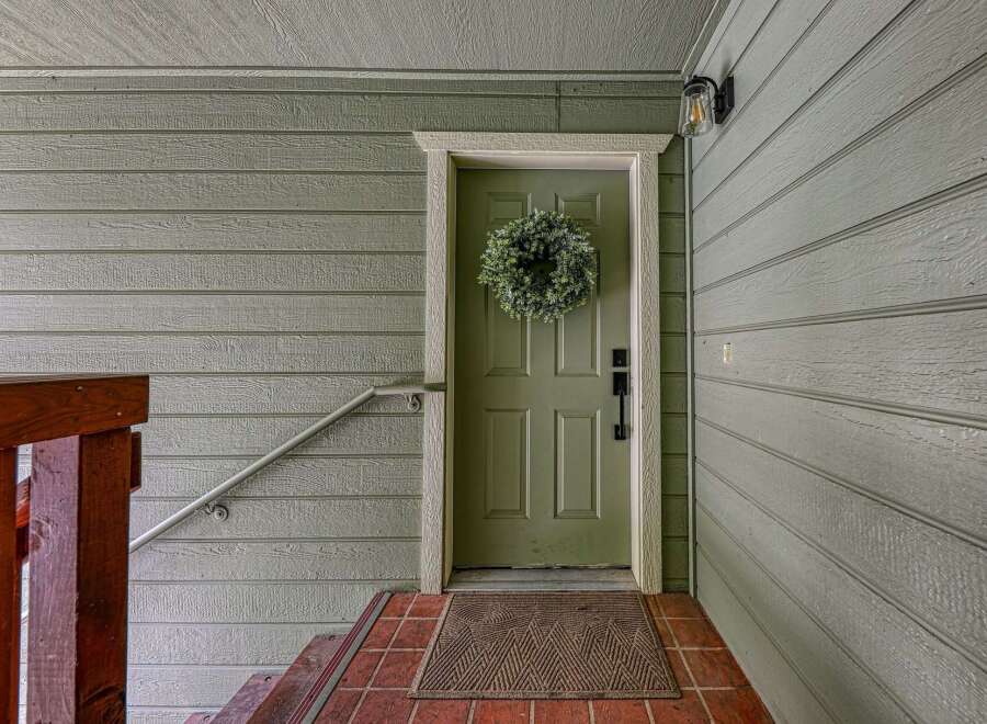 Welcome guests with this charming front entrance, featuring a classic green door adorned with a lush wreath.