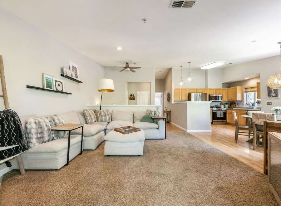 This open-concept living space features a spacious sectional sofa perfect for gatherings, complemented by decorative shelves and a stylish floor lamp.