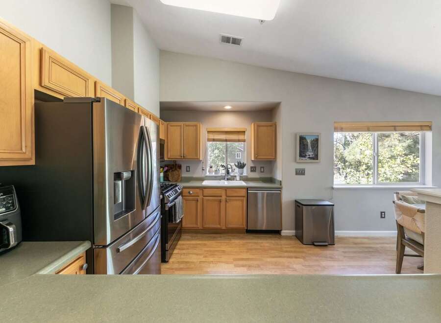 This spacious kitchen boasts modern stainless steel appliances, including a refrigerator and dishwasher, complemented by warm wooden cabinetry.