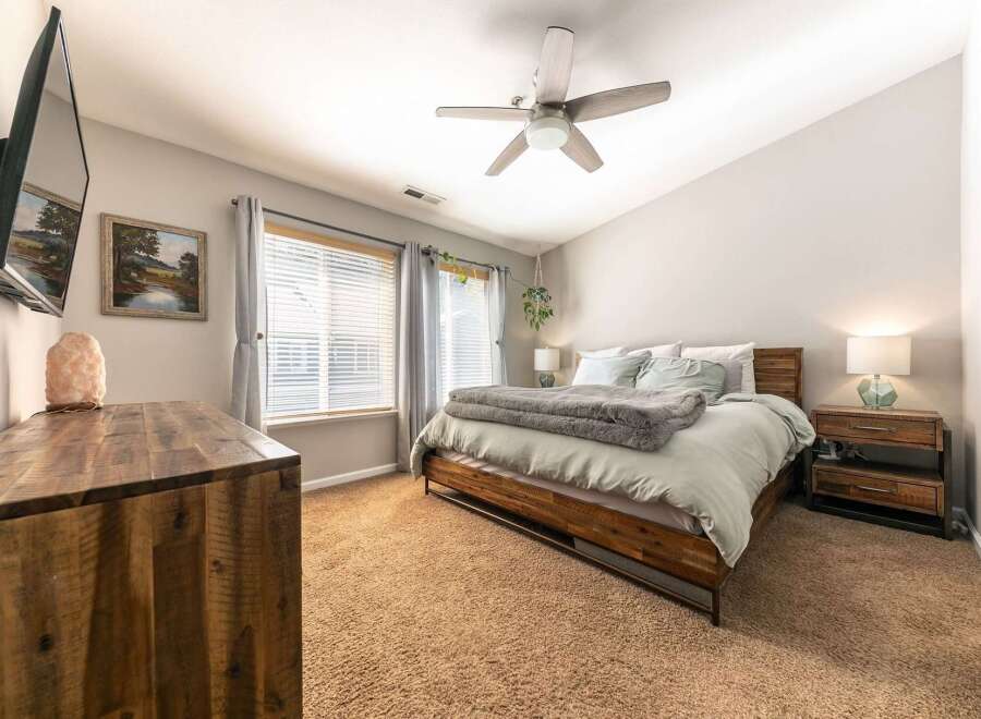 Experience comfort and style in this inviting bedroom, featuring a plush king-size bed with a cozy gray duvet and a rustic wooden frame.