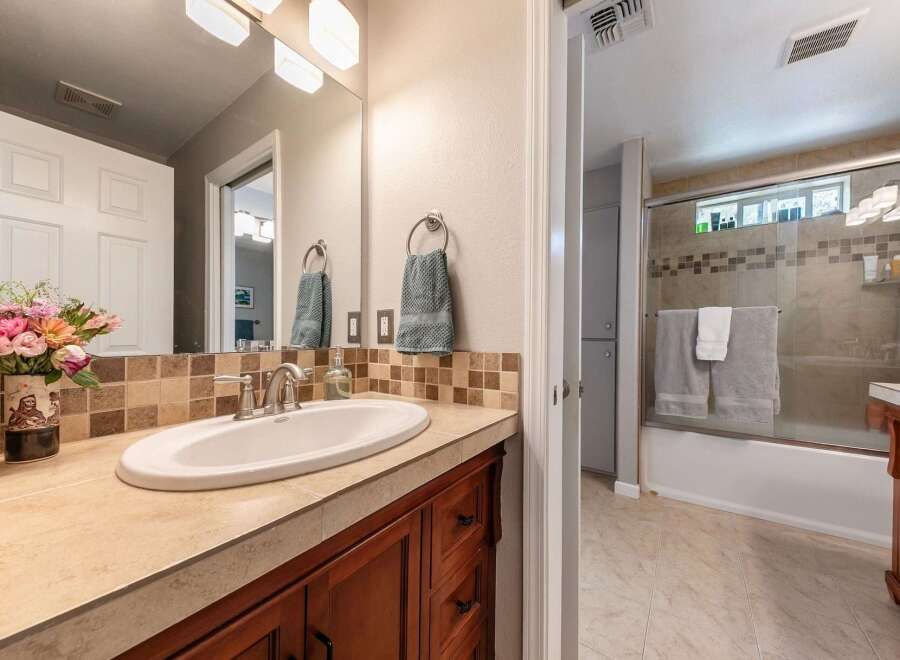 This bathroom features a spacious vanity with a white undermount sink and a tiled backsplash.
