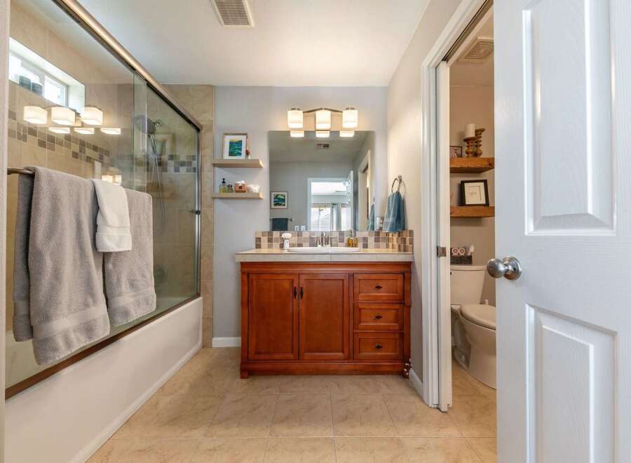 This bathroom features a spacious bathtub with a glass enclosure and convenient towel racks.