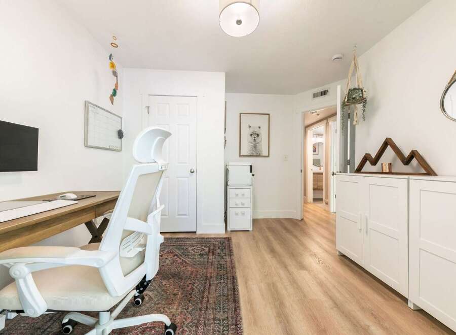 This home office features a spacious wooden desk with a modern ergonomic chair, perfect for productive workdays.