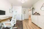 This home office features a spacious wooden desk with a modern ergonomic chair, perfect for productive workdays.