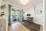 This home office features a large sliding glass door that opens to a private balcony, perfect for enjoying the outdoors.