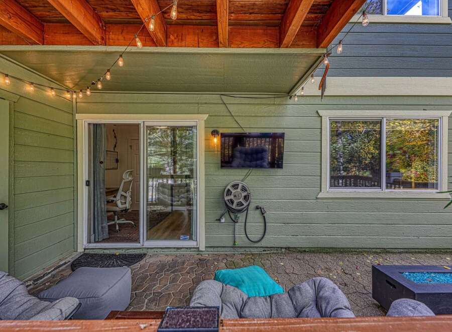 Enjoy outdoor entertainment with this covered patio featuring a mounted flat-screen TV and comfortable seating.