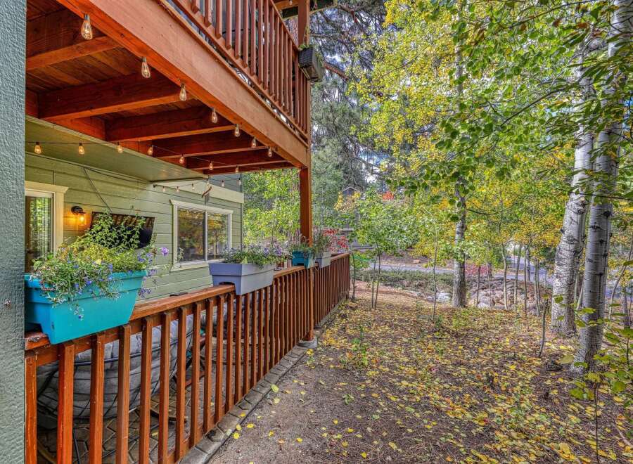 Enjoy the crisp autumn air from this charming home featuring a spacious upper deck and a cozy lower porch adorned with string lights.