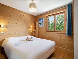 Experience cozy mountain living in this charming bedroom, featuring warm wood-paneled walls and a comfortable queen-sized bed.