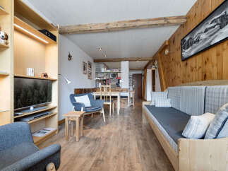 Experience cozy living in this charming mountain retreat, featuring a spacious living area with a comfortable sofa and armchair, perfect for relaxing after a day on the slopes.