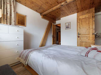 Experience cozy living in this charming bedroom featuring a comfortable bed with striped linens and decorative pillows.