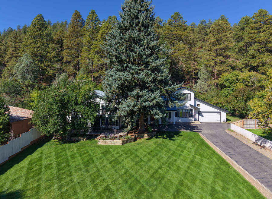 Nestled against a backdrop of lush pine trees, this stunning property offers a serene escape.