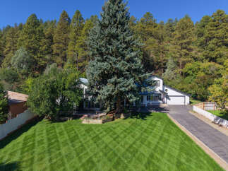 Nestled against a backdrop of lush pine trees, this stunning property offers a serene escape.