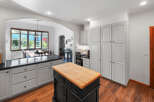 This spacious kitchen boasts ample storage with a wall of white cabinets and a large island featuring a butcher block countertop.