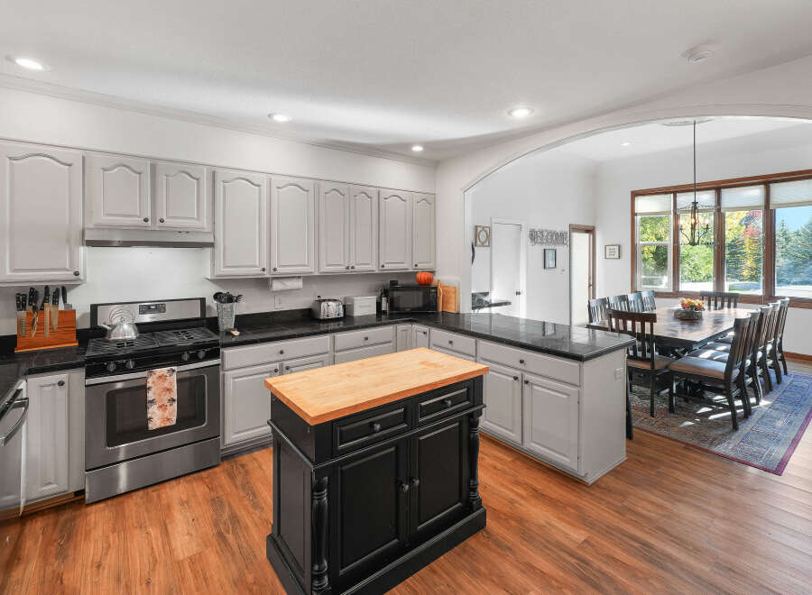 This spacious kitchen boasts ample cabinet space with a light gray finish and a large black island topped with a butcher block.