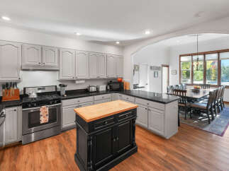 This spacious kitchen boasts ample cabinet space with a light gray finish and a large black island topped with a butcher block.