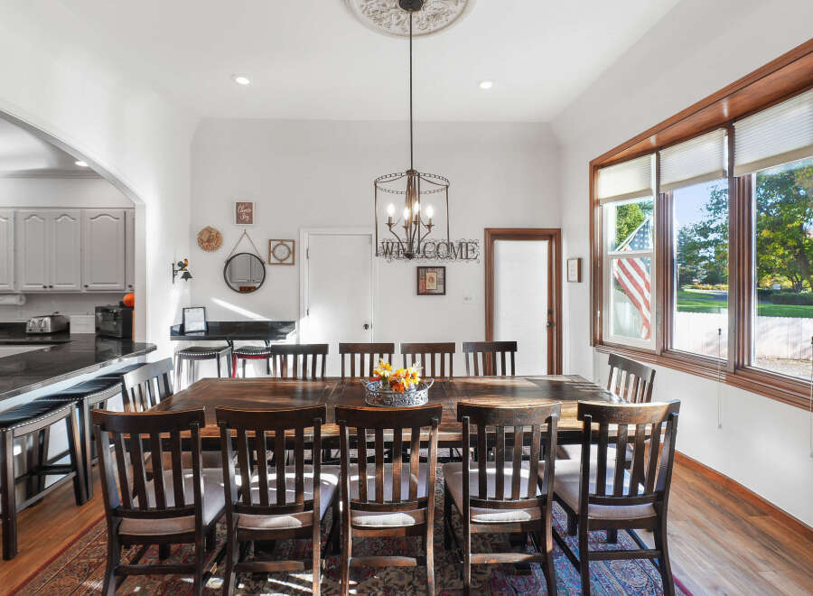 This spacious dining room features a large, rustic wooden table surrounded by dark wood chairs, perfect for hosting family gatherings.