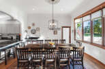 This spacious dining room features a large, rustic wooden table surrounded by dark wood chairs, perfect for hosting family gatherings.