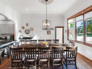 This spacious dining room features a large, rustic wooden table surrounded by dark wood chairs, perfect for hosting family gatherings.