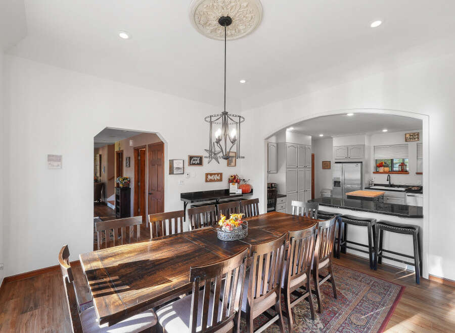 This spacious dining room features a large, rustic wooden table with seating for eight, perfect for family gatherings.